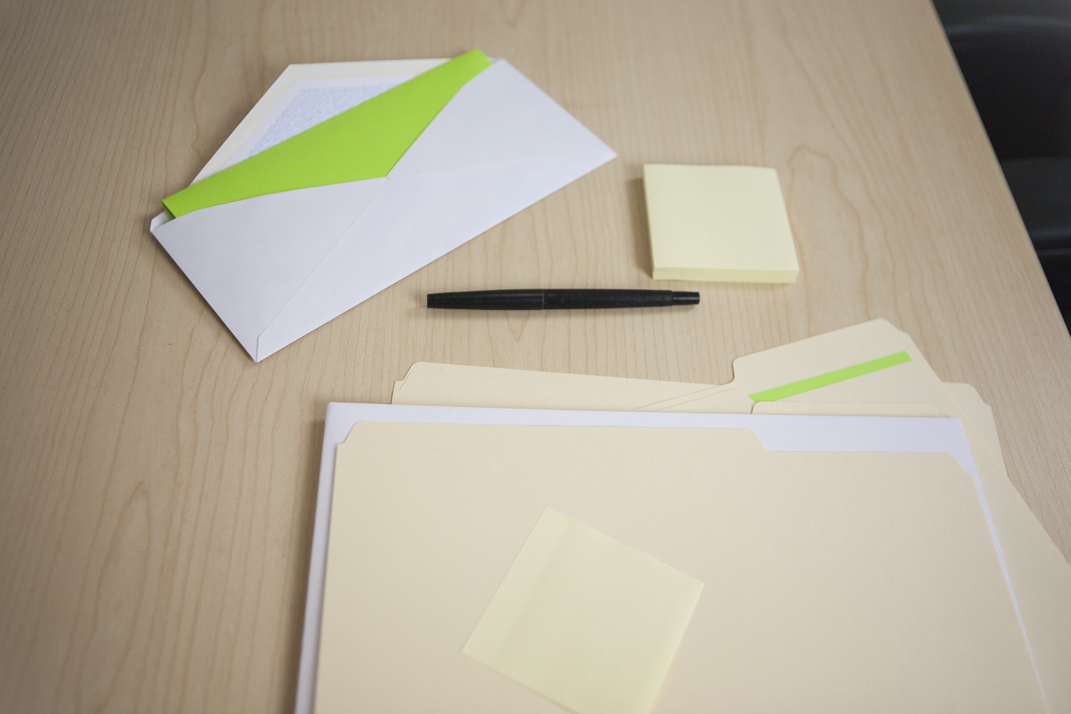 Manila folder, envelope, and some other office supplies on desk.